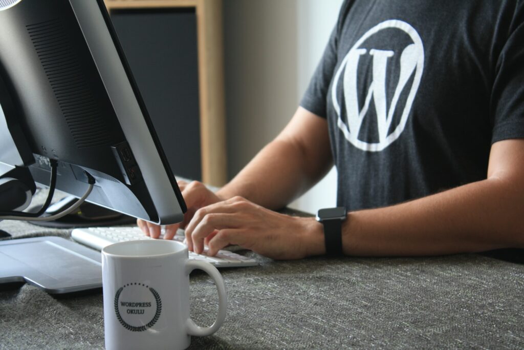 Wordpress のロゴが入ったコンピューターを使用している男性。